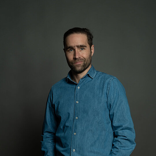 A man with dark hair in a blue shirt.